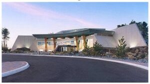 A large building with a green roof and a parking lot.