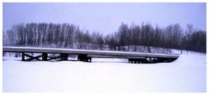 A long trailer truck driving down the road in winter.