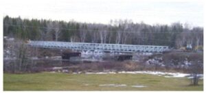 A bridge over water with trees in the background.